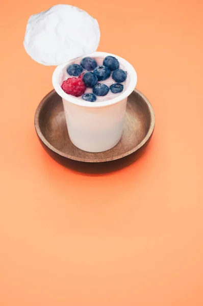 Yogur Bayas Una Taza Plástico Sobre Fondo Naranja — Foto de Stock