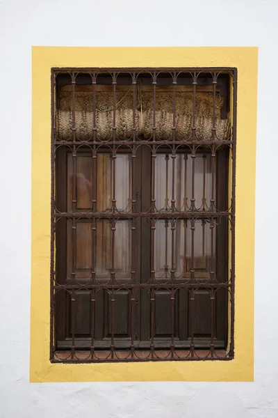 Beyaz Bir Duvarda Sarı Renkli Metal Parmaklıkları Olan Bir Pencere — Stok fotoğraf