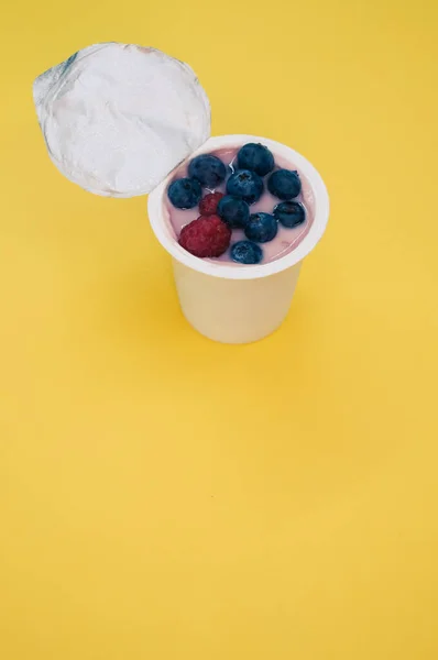 Iogurte Baga Uma Xícara Plástico Fundo Amarelo — Fotografia de Stock