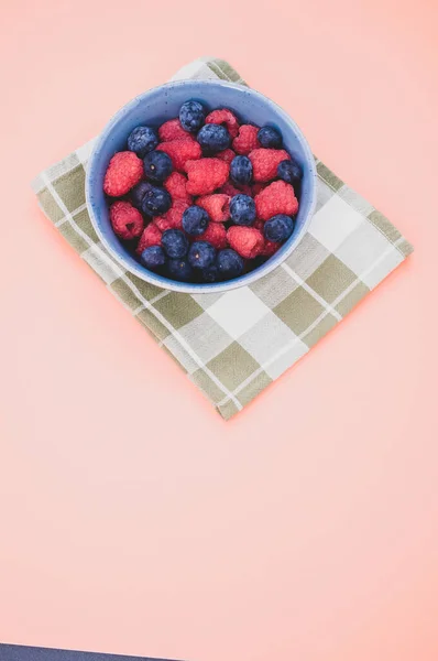用粉色背景隔开的一碗蓝莓和覆盆子的垂直照片 — 图库照片