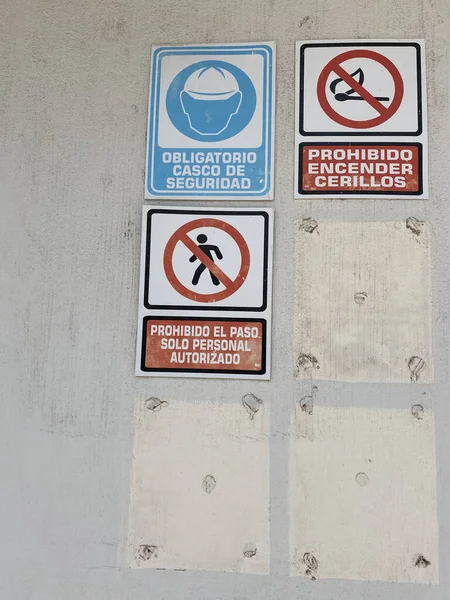 A closeup of prohibiting signs on the wall, No Trespassing, Forbidden to light matches, Protective safety helmet must be worn.