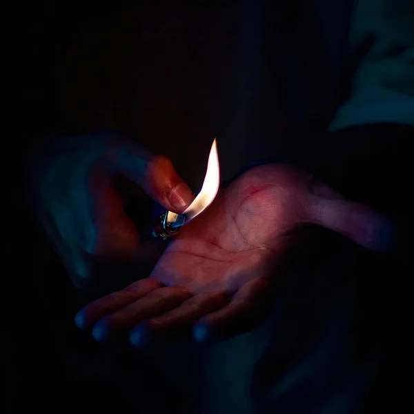 暗闇の中でライターを使った男の手のクローズアップ — ストック写真