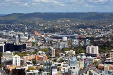 BRISBANE, AUSTRALIA - Aug 14, 2014: A high angle panoramic view of the city of Brisbane with the mountains on the horizon in the distance. clipart