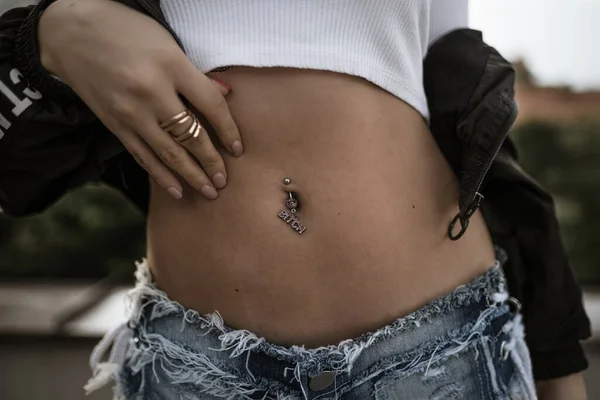 A closeup shot of a female belly with a navel piercing