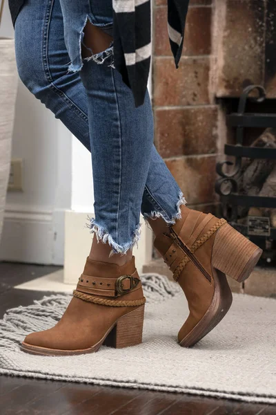 A vertical shot of a woman wearing boots indoors