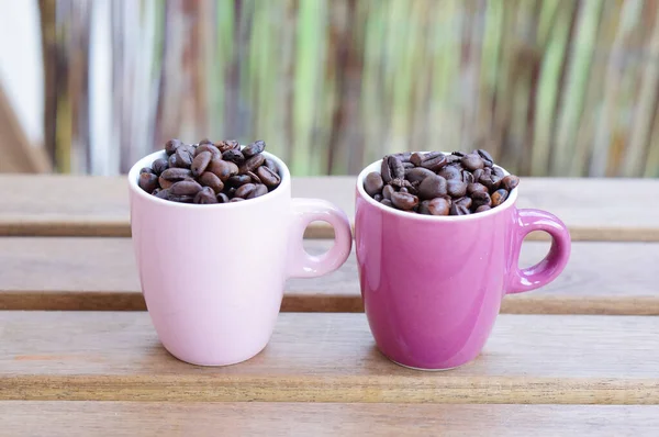Ahşap Bir Yüzey Üzerinde Pembe Fincanlar Içinde Kahve Çekirdeklerini Yakından — Stok fotoğraf