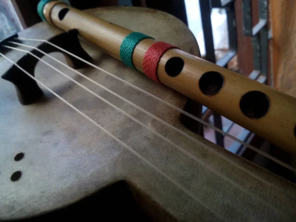 A closeup of wooden Ukulele and flute musical instruments on the table