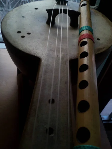 A vertical shot of wooden Ukulele and flute musical instruments on the table