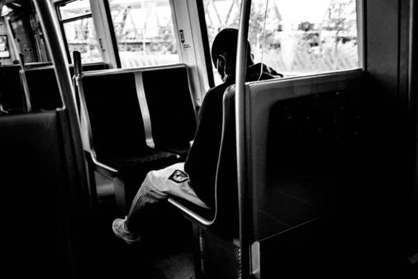 一个身穿卫生巾独自坐在公共汽车上的黑人的灰度照片 这是新的正常照片 — 图库照片