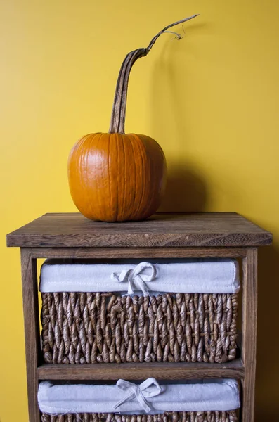 Een Pompoen Een Houten Tafel Met Een Gele Muur Achtergrond — Stockfoto