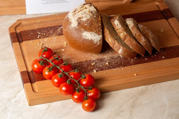 在木板上的新鲜切片面包和樱桃西红柿的特写镜头 — 图库照片
