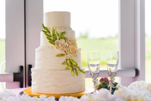 The four-tier cake with two glasses on the table
