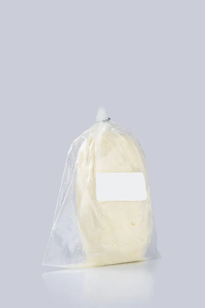 蓝色底色塑料袋里的白色乳酪的垂直照片 — 图库照片