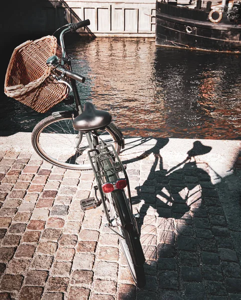 在运河旁边的鹅卵石路面上停着一辆装有篮子的自行车 — 图库照片