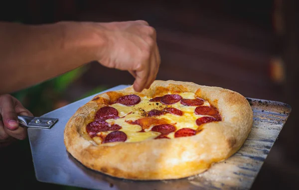 男性の手料理のピザペパロニの選択的フォーカスショット — ストック写真