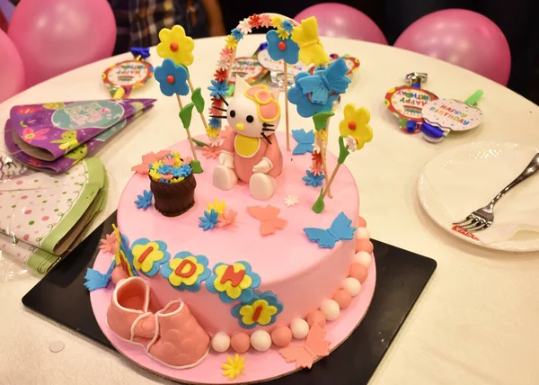 風船の誕生日キャップバッジやプレートなどの小道具が用意されているテーブルの上でカットされた子供のための美しい誕生日ケーキ — ストック写真