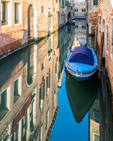 イタリアのヴェネツィアの建物に囲まれた運河上のボートの垂直ショット — ストック写真