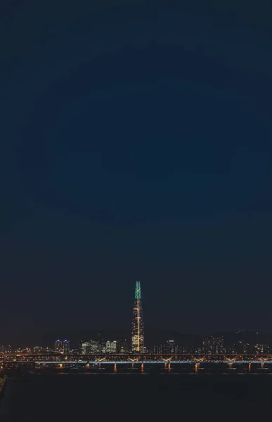 Eine Vertikale Aufnahme Der Beleuchteten Stadt Bei Nacht — Stockfoto