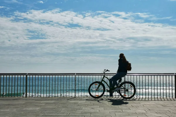 多云的一天 一个骑自行车的人背着背包在海滨拍了一张特写照片 — 图库照片