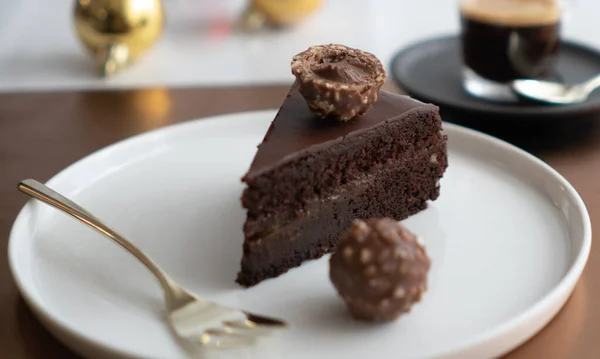 フェレーロ ローチャーとエスプレッソと呼ばれるオーストリアのダークチョコレートケーキのスライスは 白いプレートの上に静止します — ストック写真