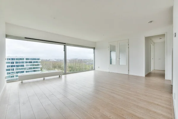 an empty white room with laminate flooring, french windows and doorless entrance