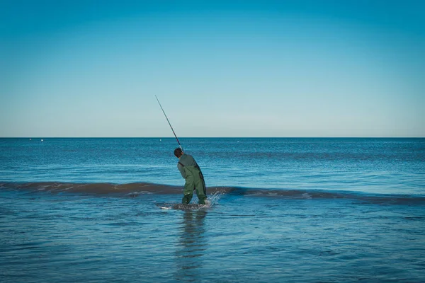 Homem Que Pesca Intensamente Mar Azul Enquanto Marés Lavam Sobre — Fotografia de Stock