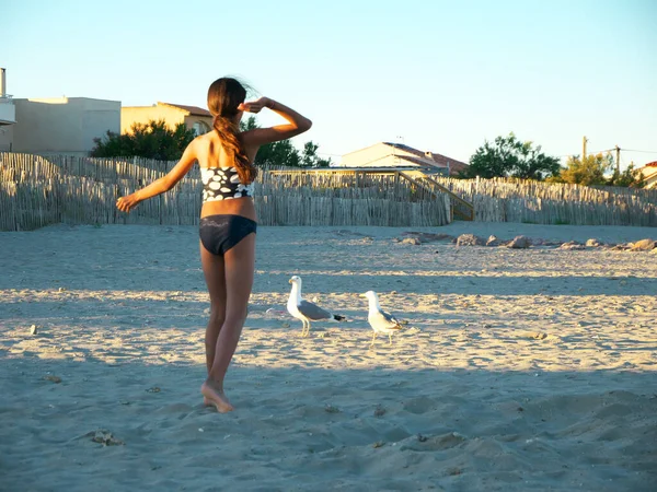 一个可爱的女孩在海滩上喂海鸥 — 图库照片