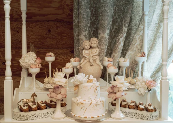 誕生日パーティーで甘いに囲まれた双子の赤ちゃん天使の像の前でおいしい白いケーキ — ストック写真