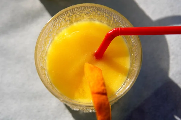 一个充满活力的新鲜橙色鸡尾酒的顶部视图 配上塑料红色稻草和一片橙子 — 图库照片