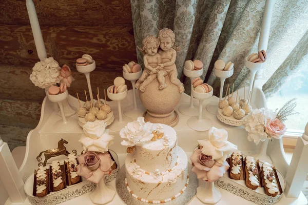 Piękny Biały Tort Otoczony Pysznymi Słodyczami Przed Statuetkami Anioła Eleganckiej — Zdjęcie stockowe