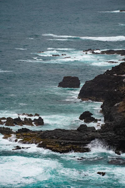 Eine Vertikale Aufnahme Von Wellen Die Einem Ufer Gegen Felsen — Stockfoto