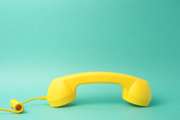 蓝绿色背景的黄色复古电话接收机 — 图库照片