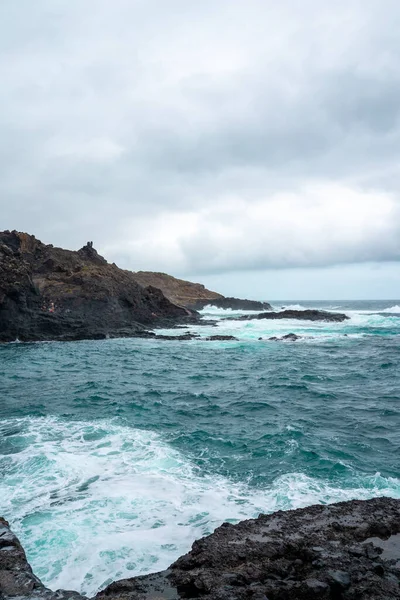 Eine Vertikale Aufnahme Von Wellen Die Einem Ufer Gegen Felsen — Stockfoto