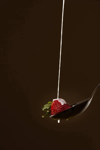 Eine Vertikale Aufnahme Einer Erdbeere Mit Milch Auf Einem Löffel — Stockfoto