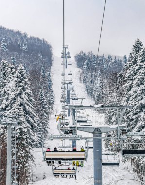 A vertical shot of a ski lift surrounded by snow-covered forest clipart