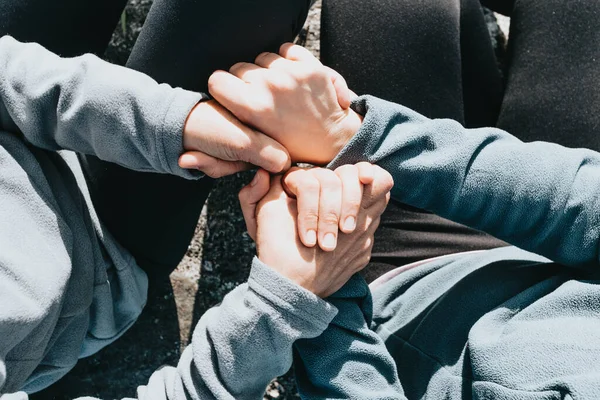 An overhead shot friends holding hands together showing love and support - mental health support concept