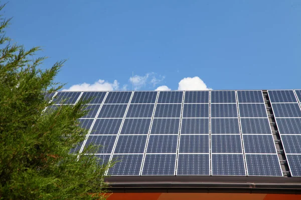 明るい空の下の屋根の上の青い太陽電池パネルの行 — ストック写真