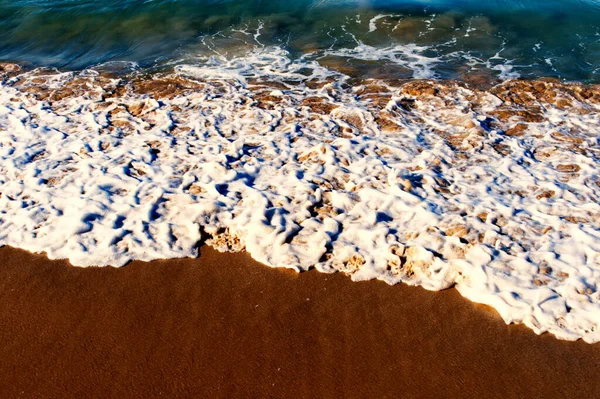 在被沙子覆盖的海滩上 一个高角的海浪拍下了泡沫般的海浪 — 图库照片