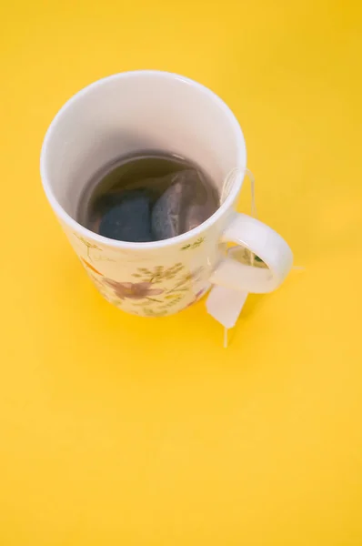 一杯热茶 茶包在黄色的背景上 有复制的空间 — 图库照片