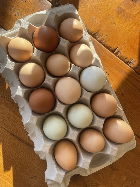 A top view of an egg carton full of eggs on a wooden table