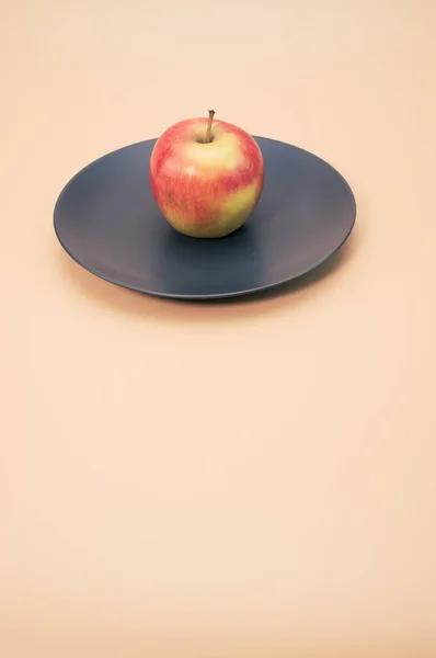 Вертикальный Снимок Свежего Яблока Черной Круглой Тарелке Изолированной Розовом Фоне — стоковое фото