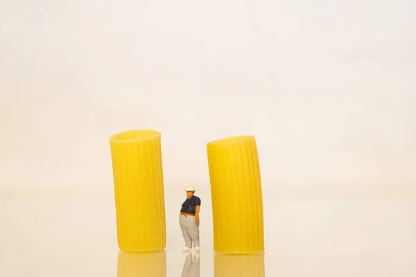 Una Figurita Miniatura Una Persona Obesa Parada Junto Pasta Rigatoni — Foto de Stock