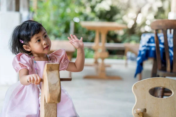 Ένα Χαριτωμένο Ασιατικό Μικρό Κορίτσι Κάθεται Ένα Ξύλινο Παιχνίδι Άλογο — Φωτογραφία Αρχείου