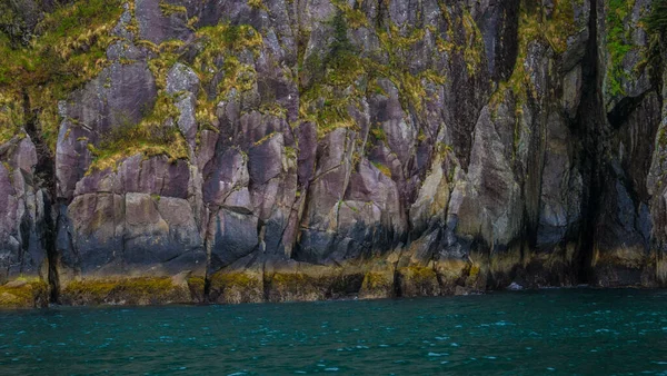 Una Scogliera Ricoperta Verde Con Strati Colorati Dall Acqua Verde — Foto Stock