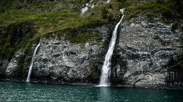 低瀑布和湖边长满青草的悬崖 — 图库照片