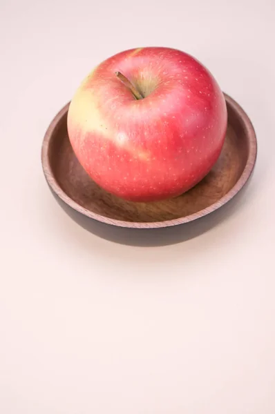 Kırmızı Elmanın Dikey Görüntüsü Ahşap Bir Kâse Üzerinde Pembe Arka — Stok fotoğraf