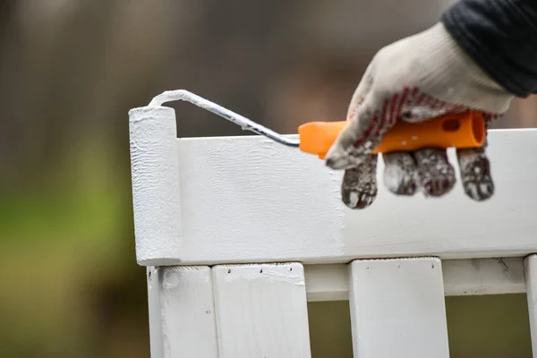 Een Man Die Tuinmeubelen Wit Schildert Met Een Verfroller — Stockfoto