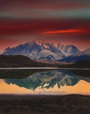 A gorgeous landscape with a red sky and rocky mountains reflected in a lake in Torres del Paine National Park, Chile clipart