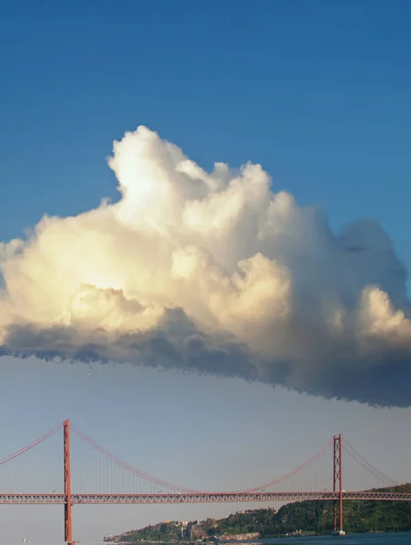 ポルトガルのリスボンにある25 Abril Bridgeは 青い空に巨大な積雲があります — ストック写真