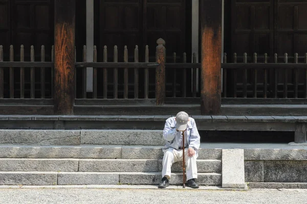 一位老人靠在手杖上休息 坐在东施台寺的台阶上 — 图库照片